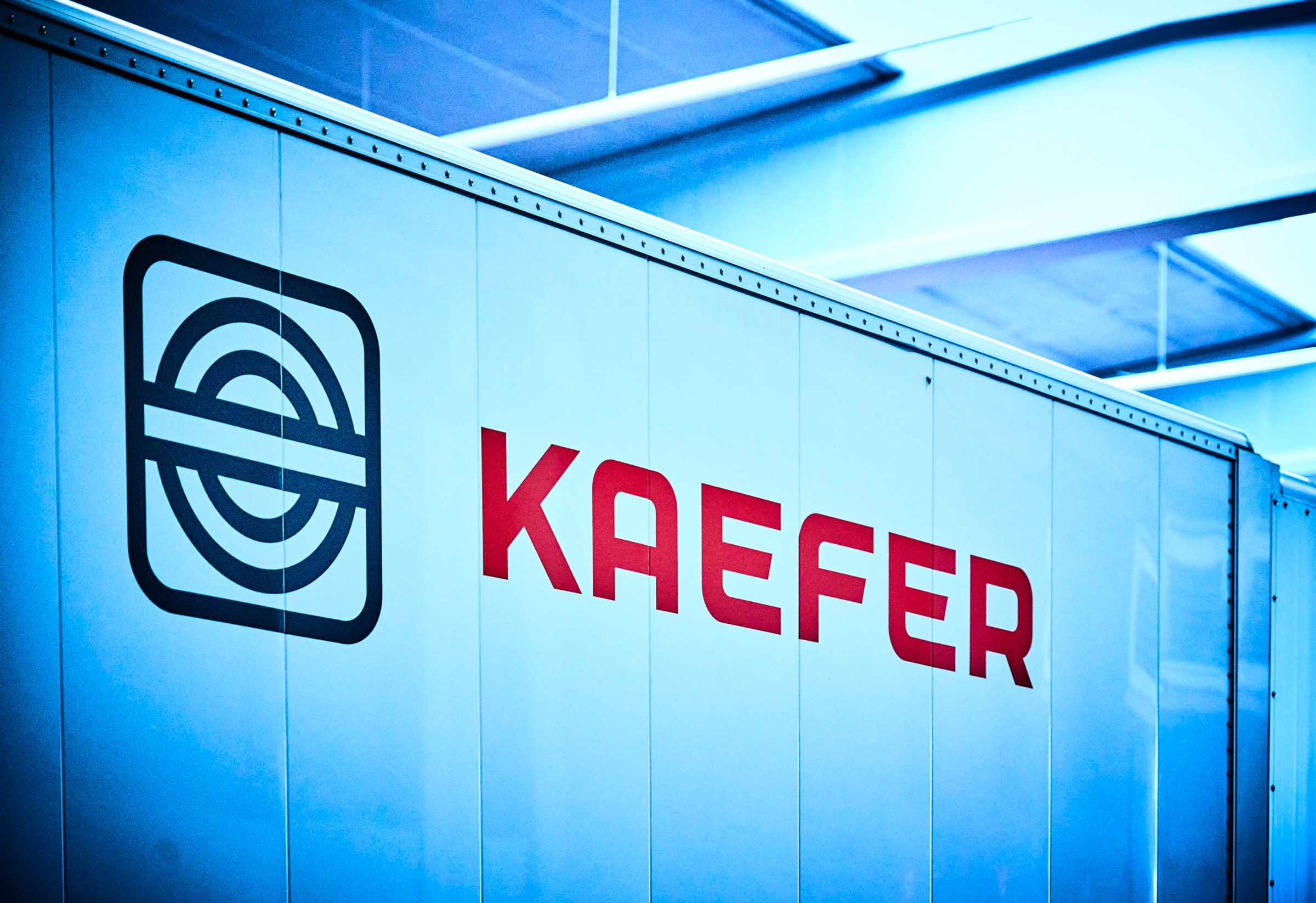 Das rote KAEFER Logo auf einer metallischen Wand