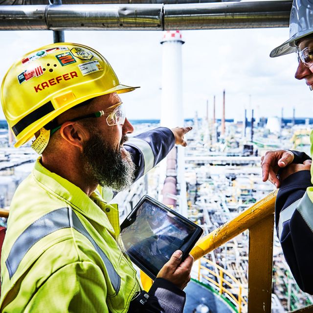 KAEFER Mitarbeiter in Arbeitsanzügen auf einer Industrieanlage