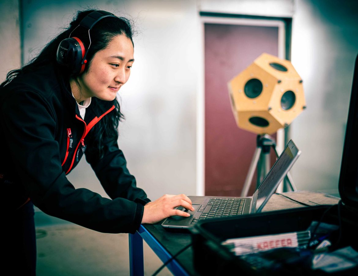 Ingenieurin bei einer akustischen Messung mit einem Dodekaeder-Lautsprecher und Laptop zur Analyse der Schalldämmung in einem Labor