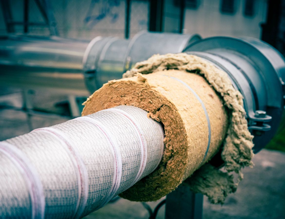 Eine horizontale Rohrleitung, die teilweise mit einer dicken Schicht aus brauner Mineralwolle umhüllt ist