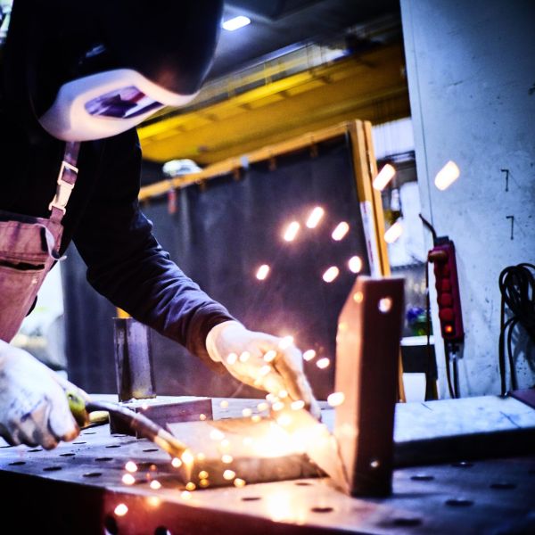 KAEFER Mitarbeiter mit Schutzmaske schweißt ein Stück Metall