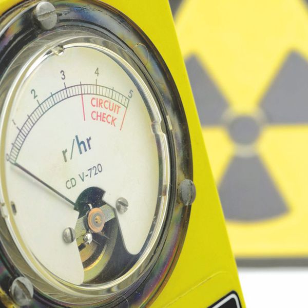 Analoges Strahlungsmessgerät CD V-720 (r/hr) vor einem gelben Warnsymbol für Radioaktivität