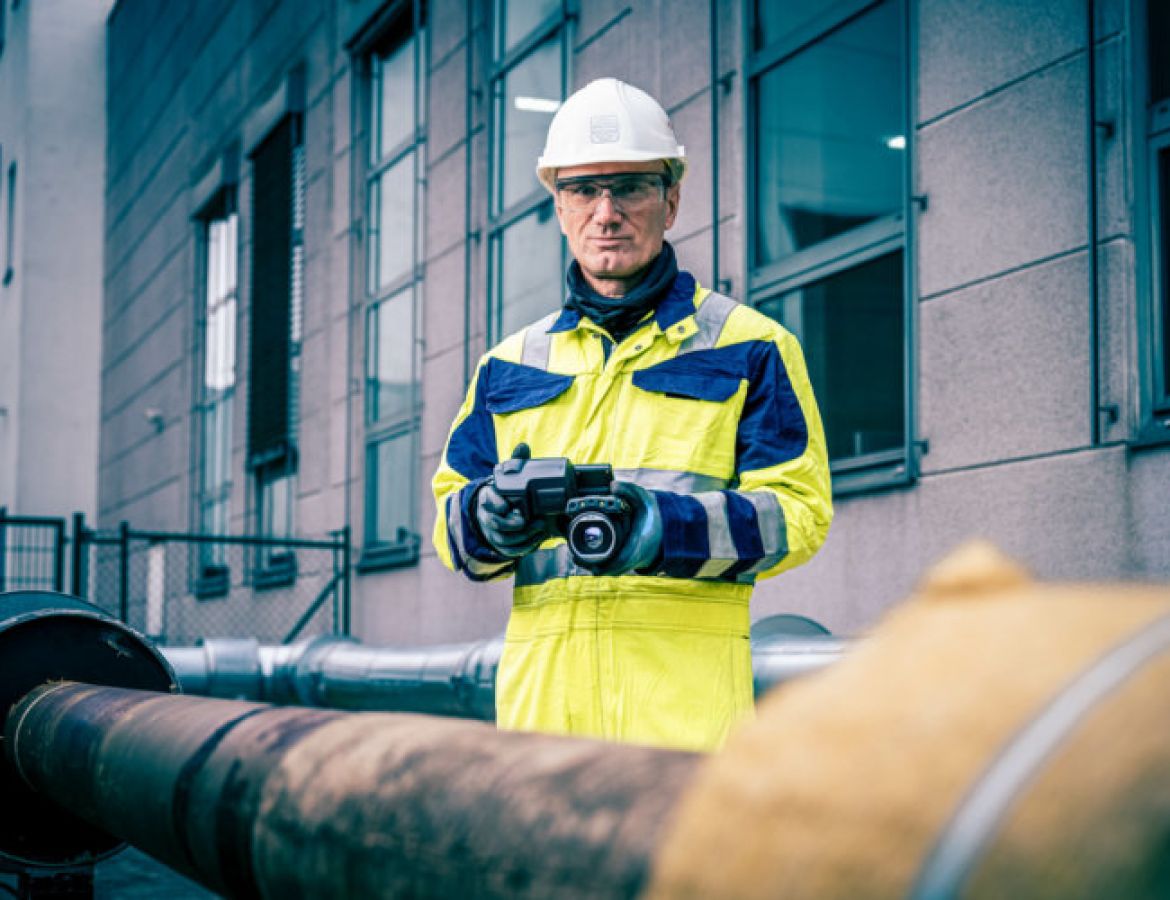 Ein KAEFER Mitarbeiter in Arbeitskleidung scannt ein Rohr mit einer Kamera