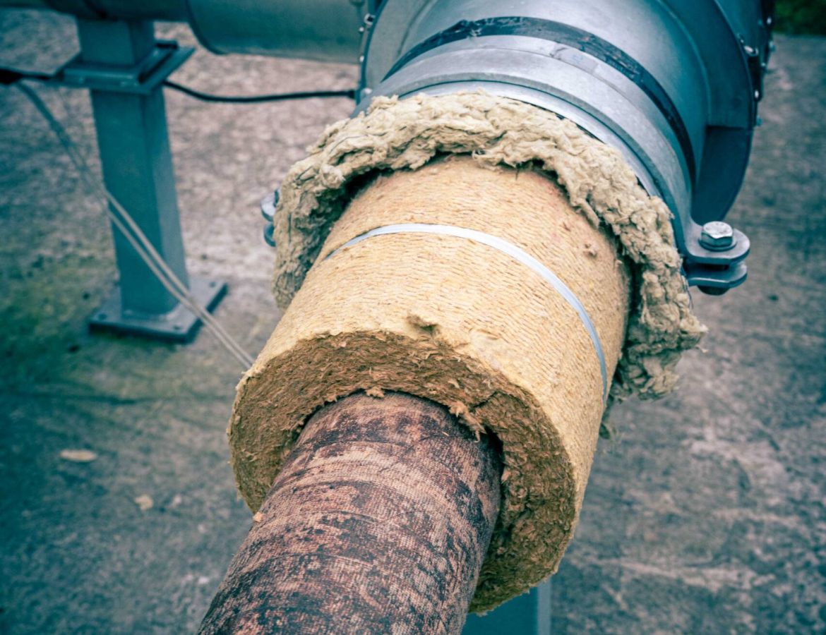 Nahaufnahme eines isolierten Industrie-Rohrsystems im Außenbereich mit Mineralwolle-Dämmung und verzinkter Blechummantelung