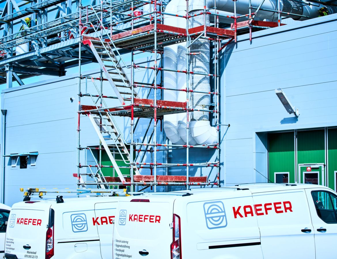 Mehrere KAEFER Transporter, die vor einem Gerüst parken